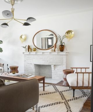Circular mirror on white fireplace hearth in Scandi-esque living room with wooden furniture and dark fabric couch.