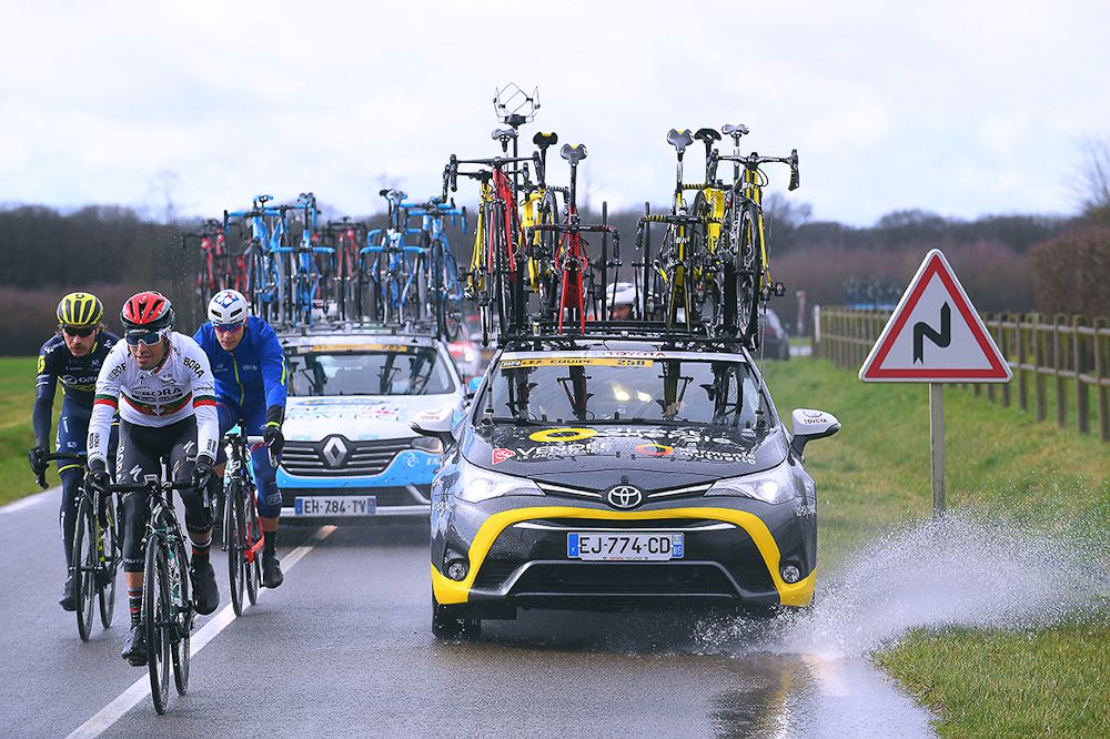 The Direct Energie team car splashes through a puddle