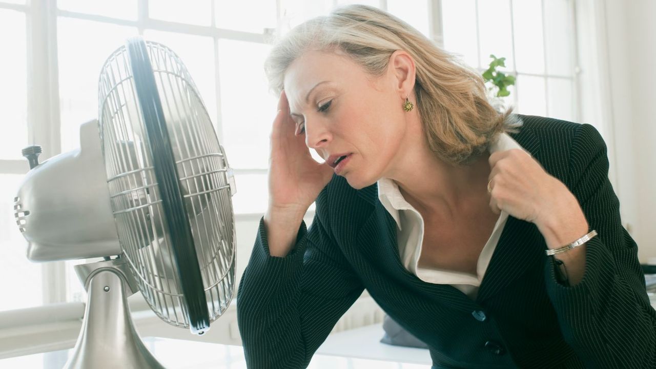 Hot businesswoman sitting in front of fan