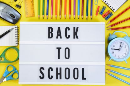 A back to school sign is surrounded by coloured pens and pencils.