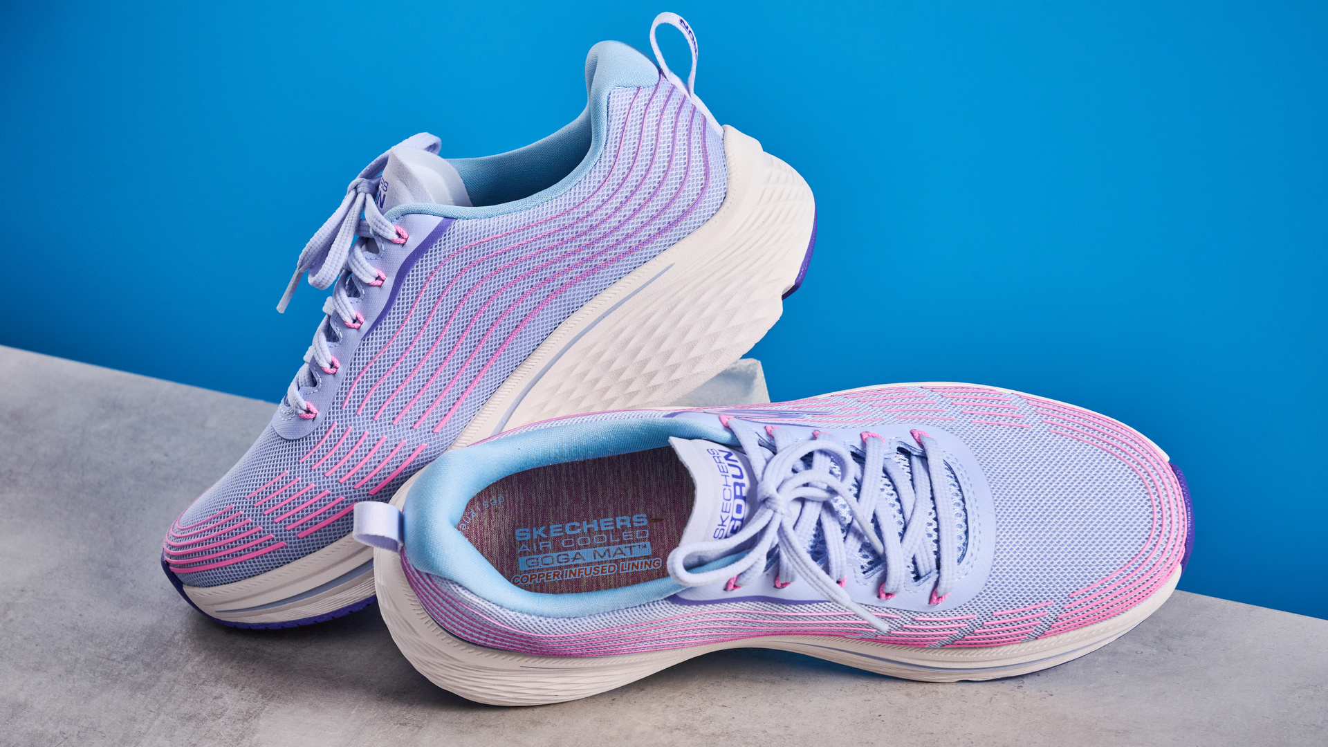 Skechers Max Cushioning Elite 2.0 running shoes photographed in front of a blue background.