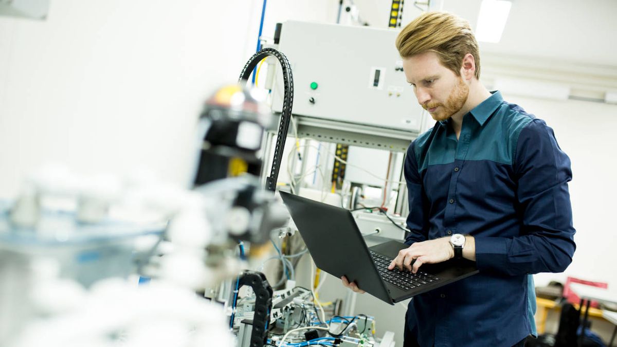 Man in blue shirt uses laptop computer to diagnose server issue