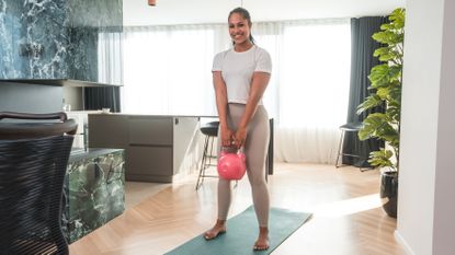 Woman holding kettlebell in domestic setting