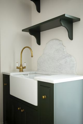 Small utility room ideas showing a uniquely shaped backsplash and a gold faucet