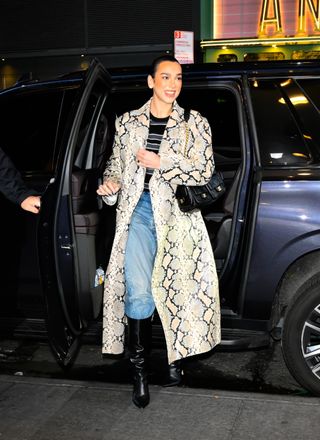 A photo of Dua Lipa dressing up in a beige snakeskin trench coat for another visit to CBS Studios.