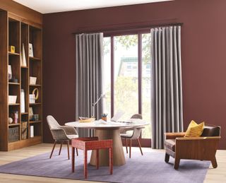 A dark red study space with a purple rug and a round table and chairs
