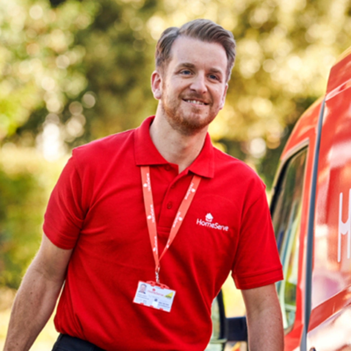 male with short hair and beard wearing red polo short, lanyard round neck, walking towards red van