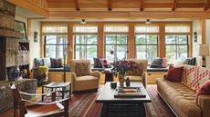 Living room of a lakeside cabin clad in pale wood with a stone fireplace