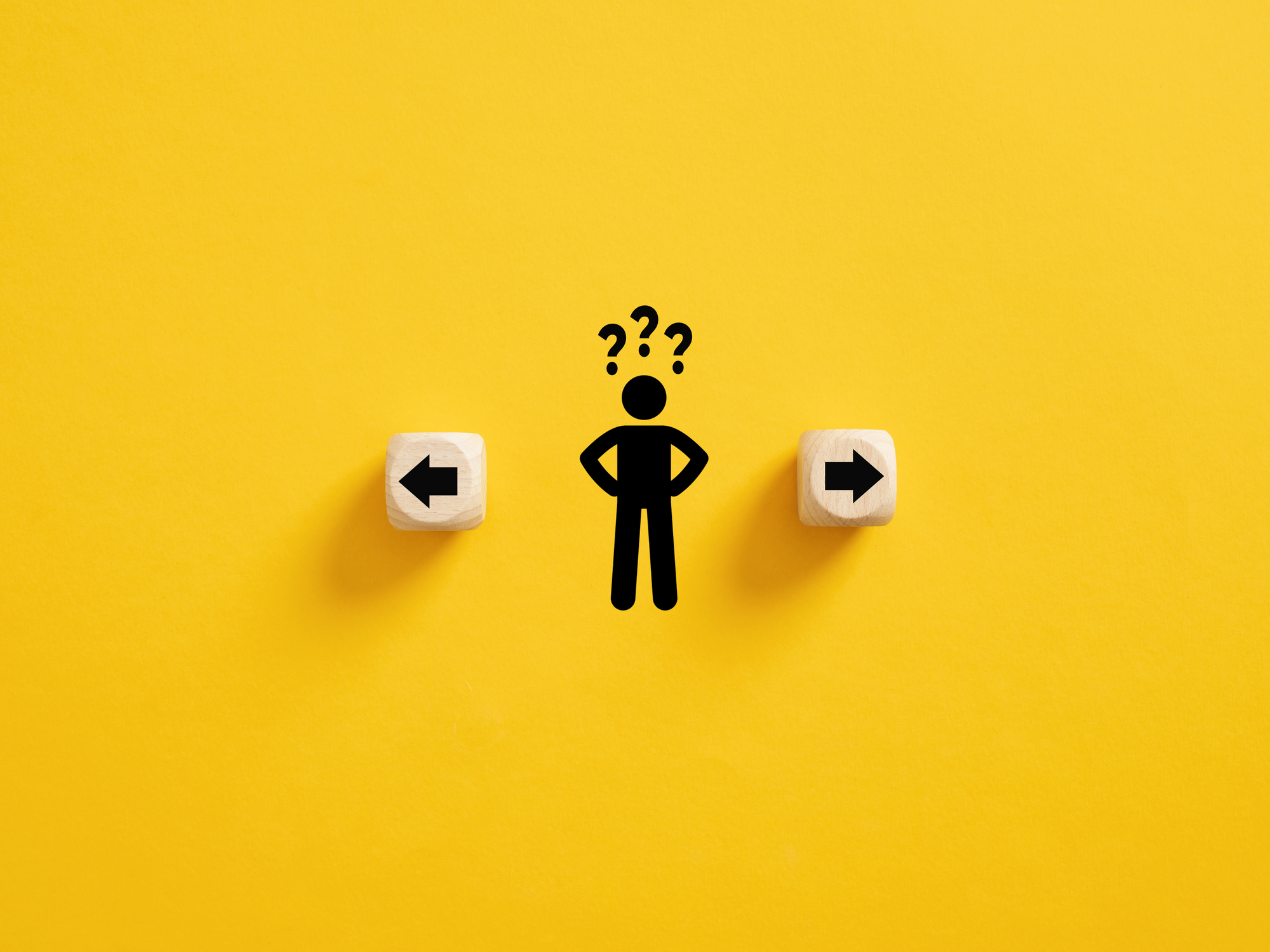 Decision making and choosing the right path. Confusion about deciding which direction to go. Stickman with question marks standing in between the wooden cubes with arrow symbols.
