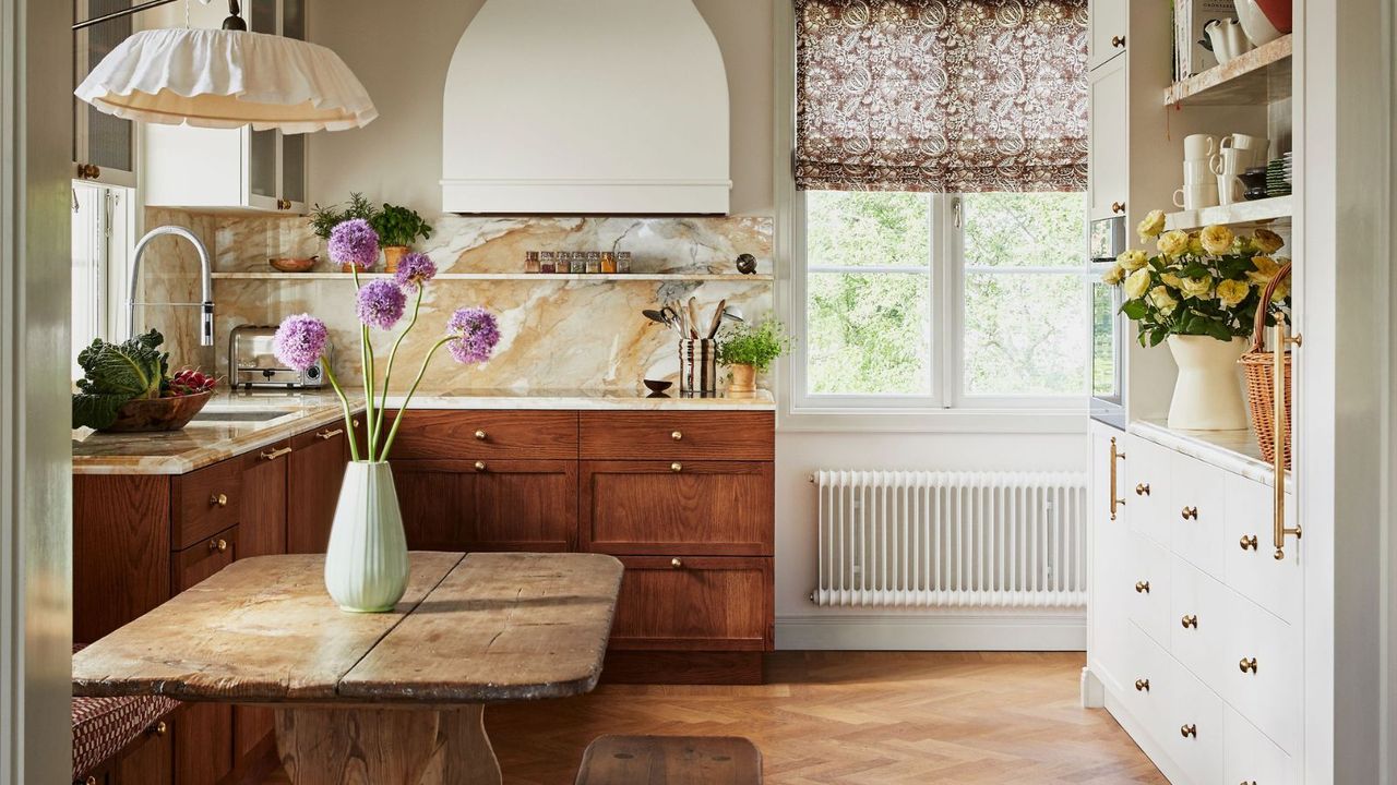 A country-style kitchen with red bottom cabinets and a kitchen table / Cathy Nordström Faye fabric credit Fanny Radvik Inuti Design