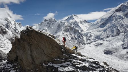 A mountainous landscape photo of two climbers climbing a peak