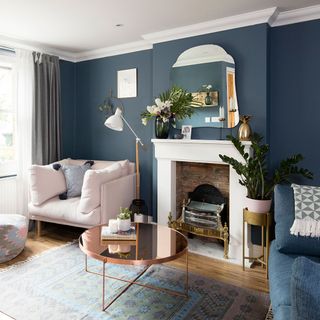 Dark blue living room with copper coffee table and a mirror above the fireplace