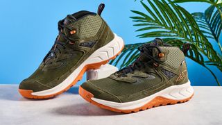 The Keen Hightrail Mid boots in Green on a stone surface against a blue background