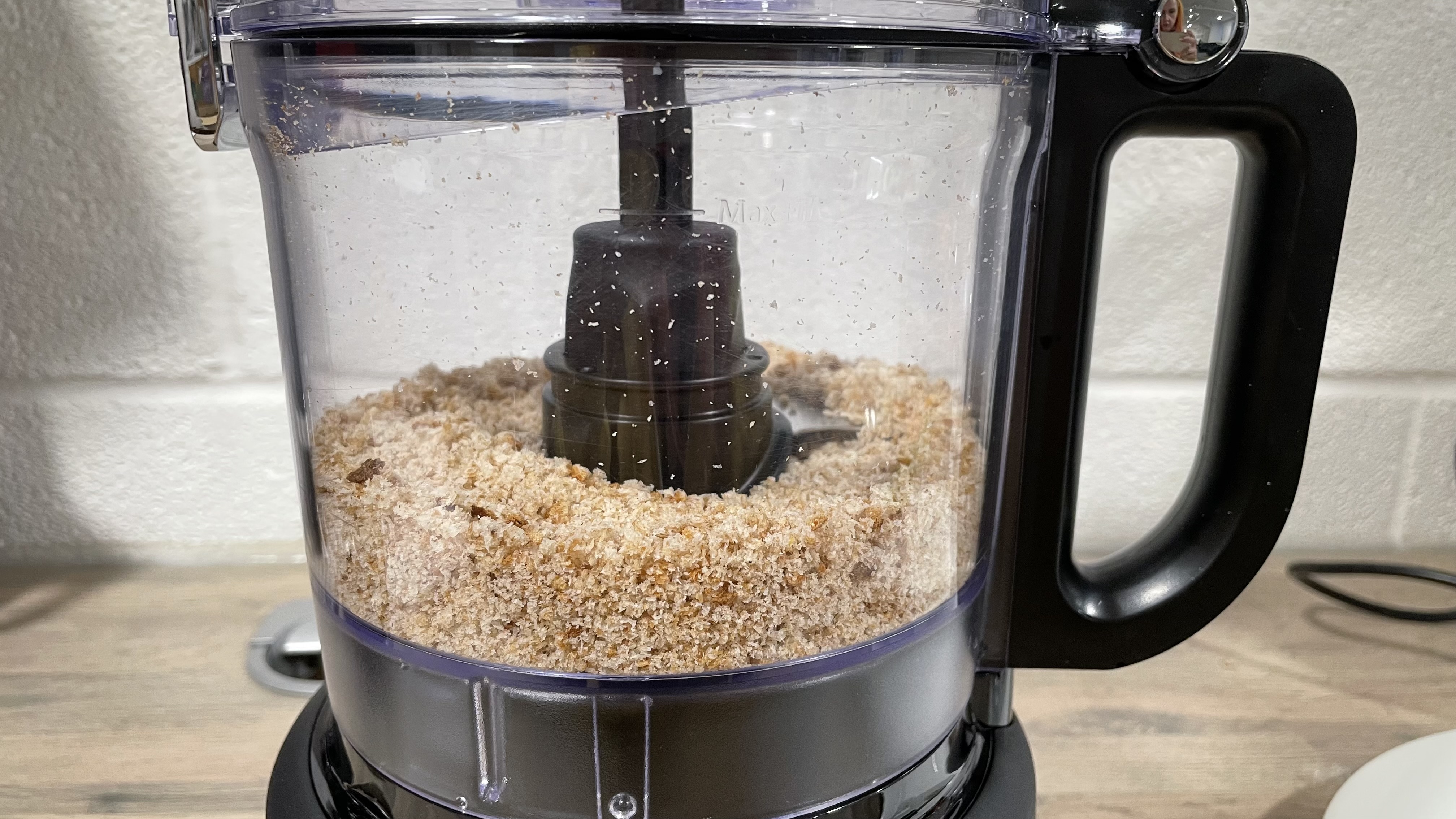 A closeup of the KitchenAid 7 cup food processor food bowl with breadcrumbs inside.