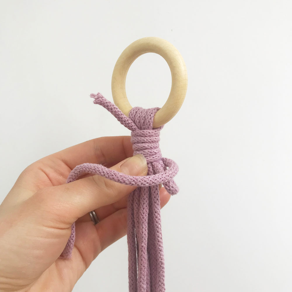 hand holding purple cord in wooden ring