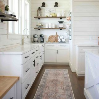 White kitchen with wooden floor with red and purple rug on the floor