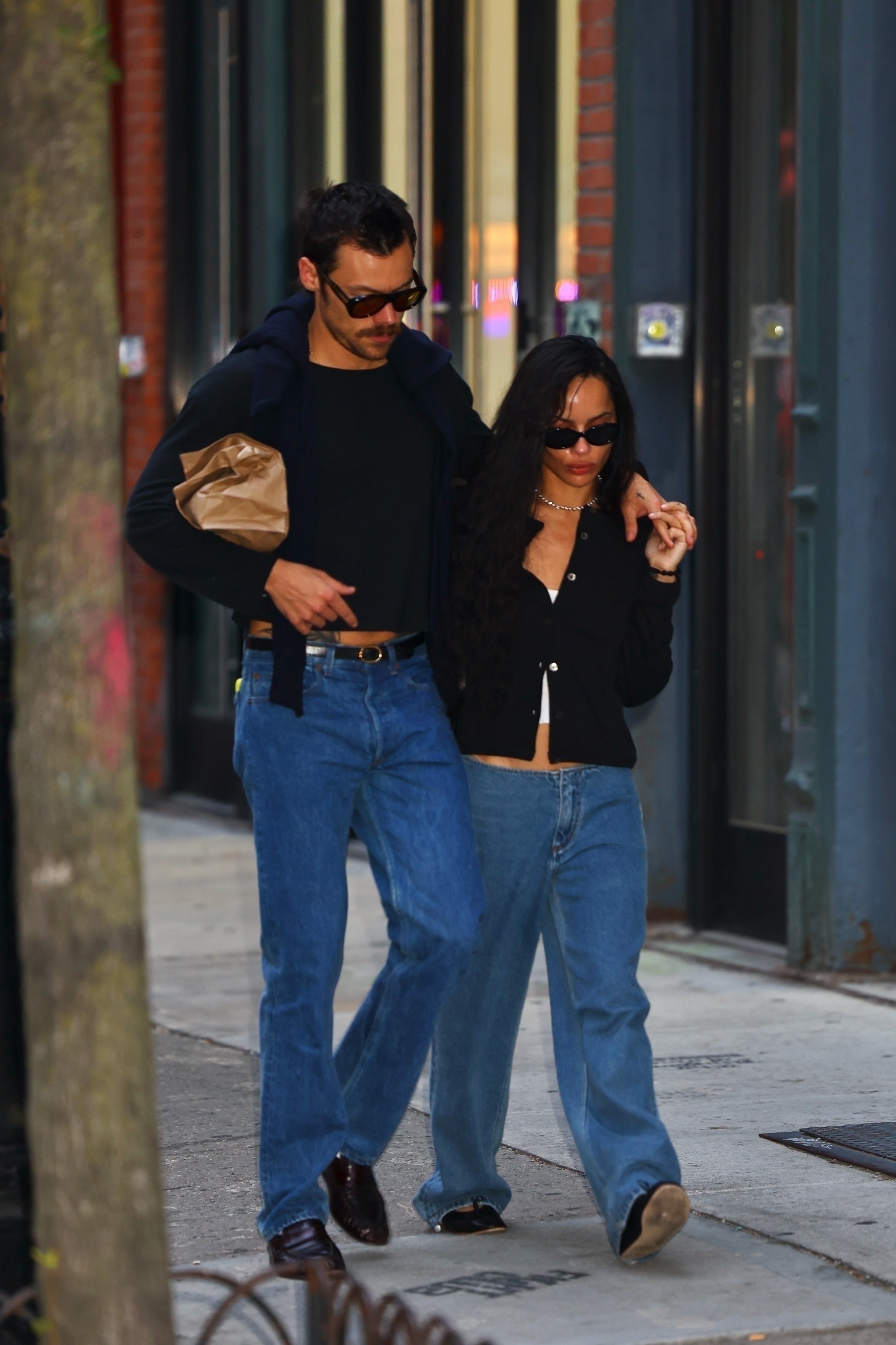 Harry styles wearing a long sleeve shirt and jeans with The Row loafers and Zoe Kravitz wearing a cardigan and jeans