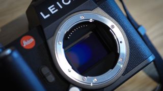 Leica SL3 camera on a wooden surface against a blue background