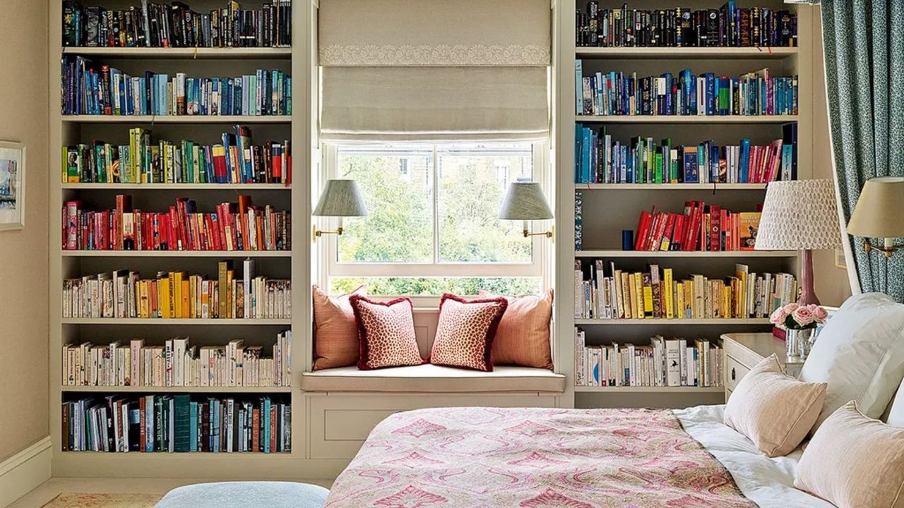 Colorful bookshelves built around a window in a traditional bedroom