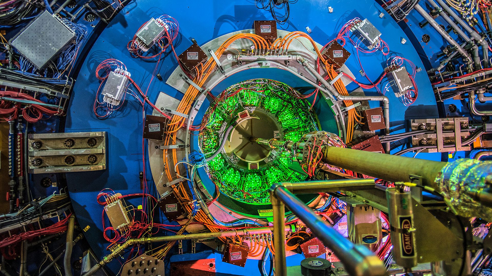 A close up of a circular collider with wires and pipes leading into it.