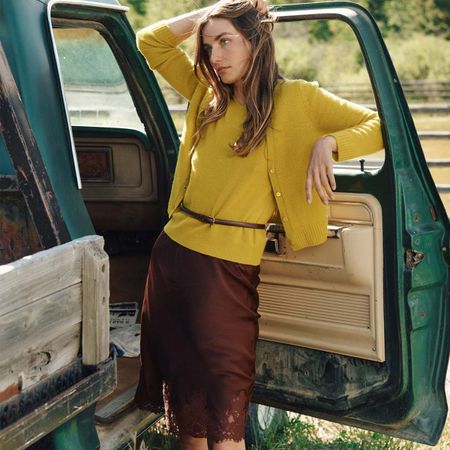 Woman in yellow knit top and brown silk skirt