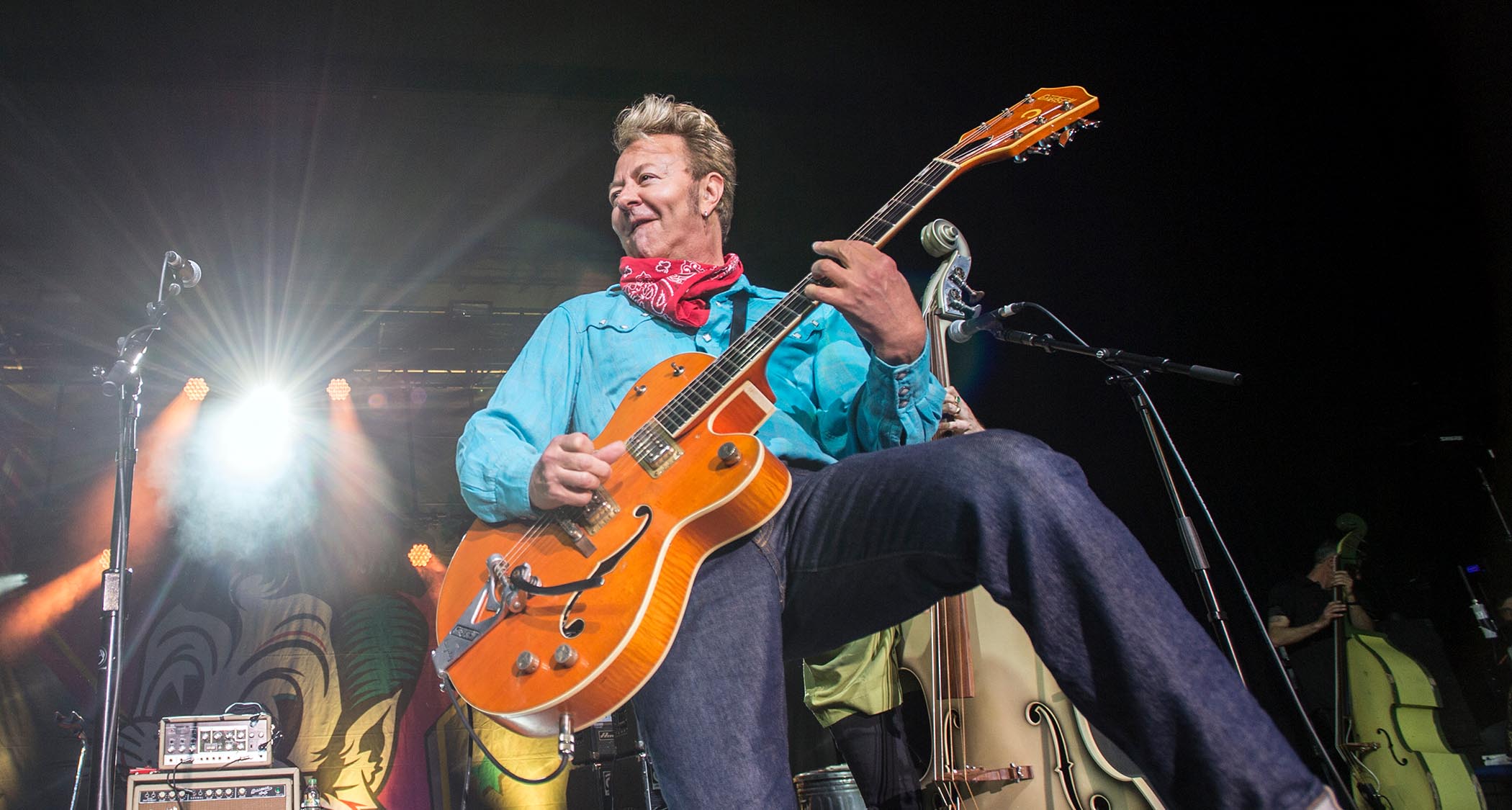 Brian Setzer wears a red neckerchief and plays a Gretsch in traditional Round-up Orange in this Stray Cats performance from 2019.