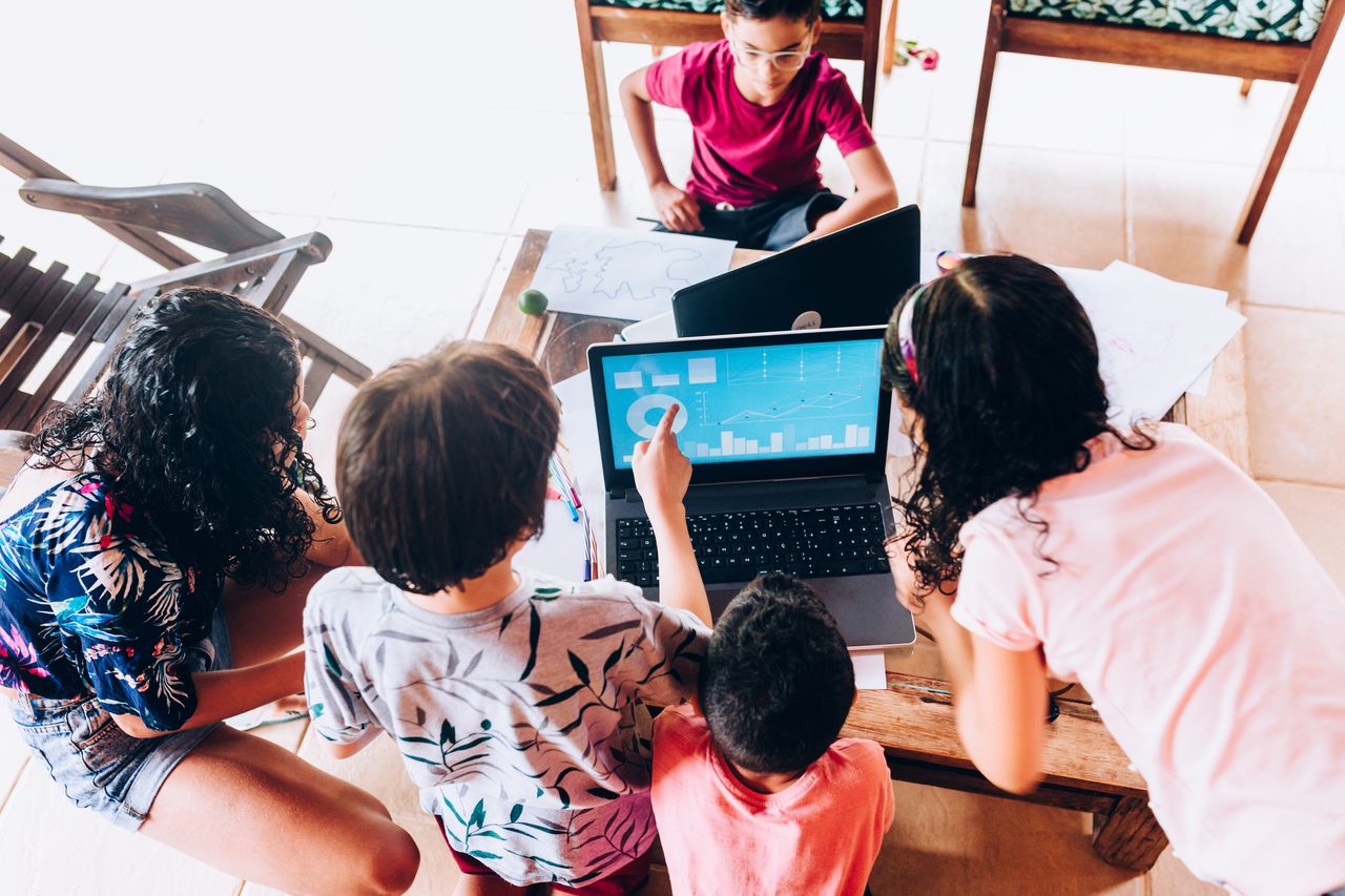 A group of kids around a computer looking at financial charts