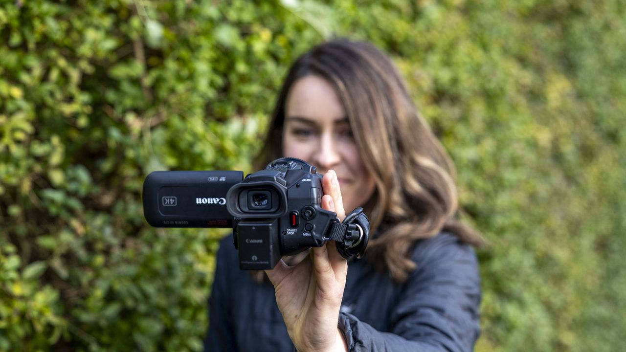 A woman holding the Canon HF G70 on a suburban street