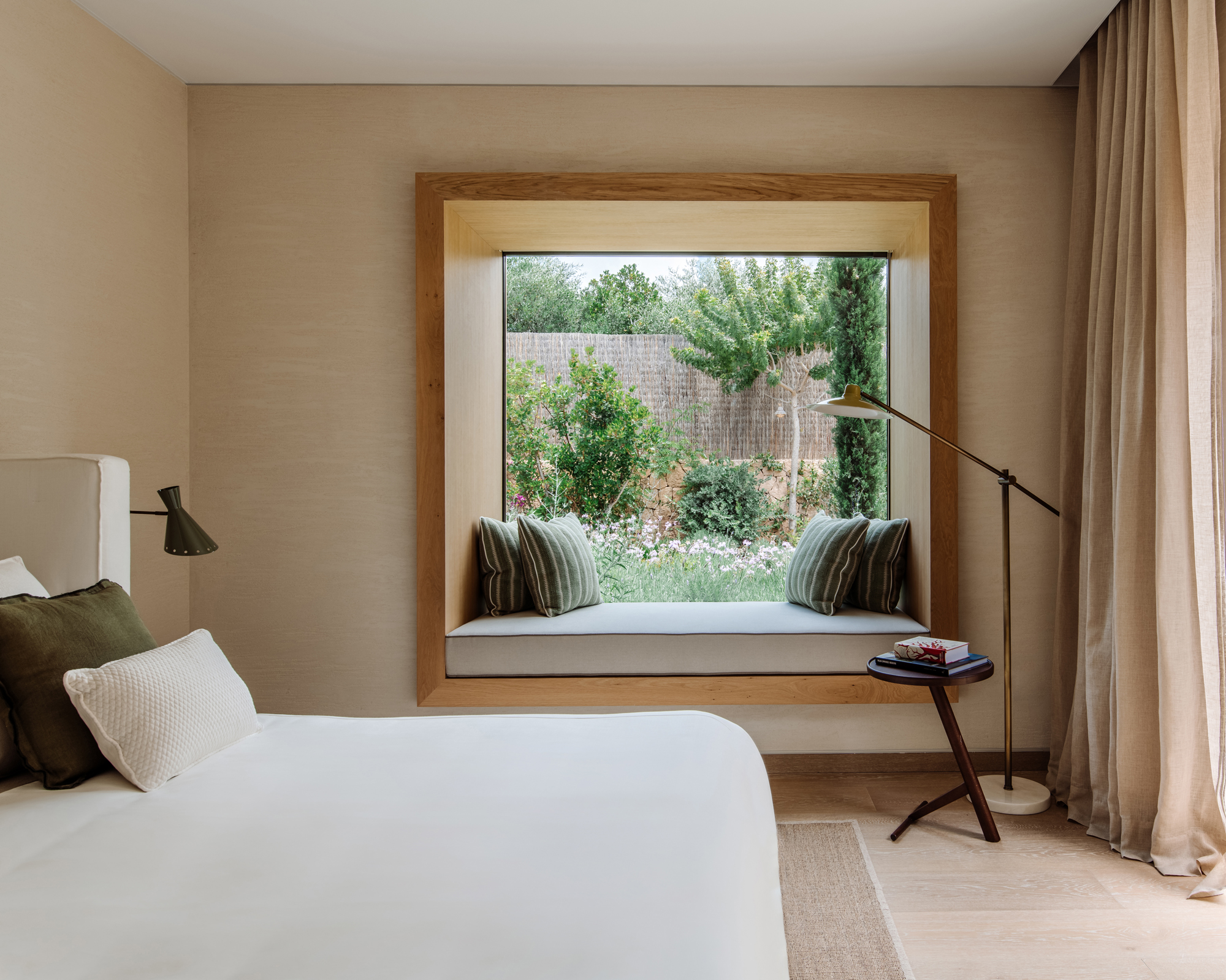 A guest bedroom in an Ibizan villa with window seat and green scatter cushions