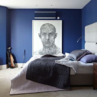 bedroom with blue wall and painting and cushions and throw