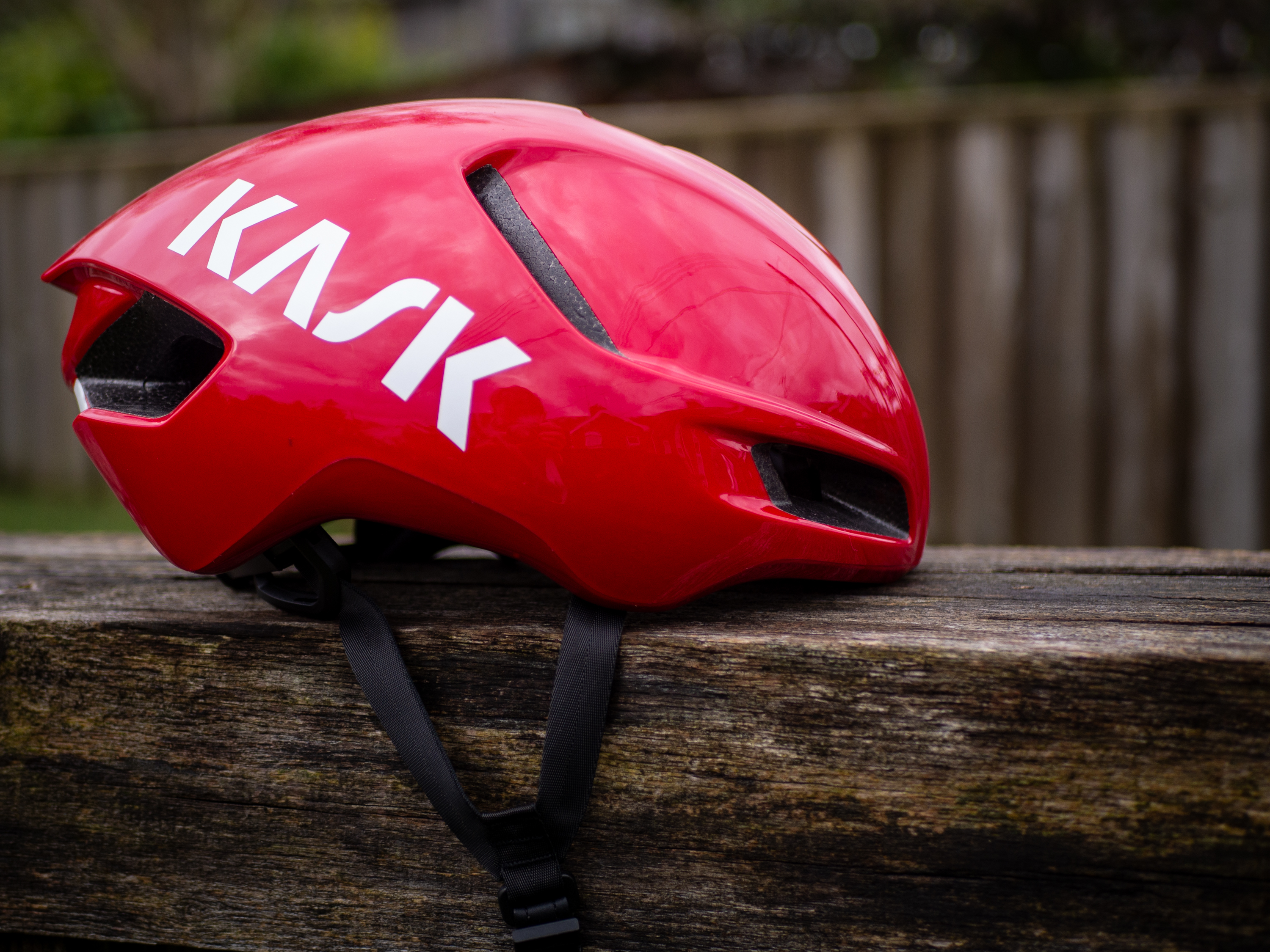 A red Kask Utopia Y aero helmet sits on a wooden bench