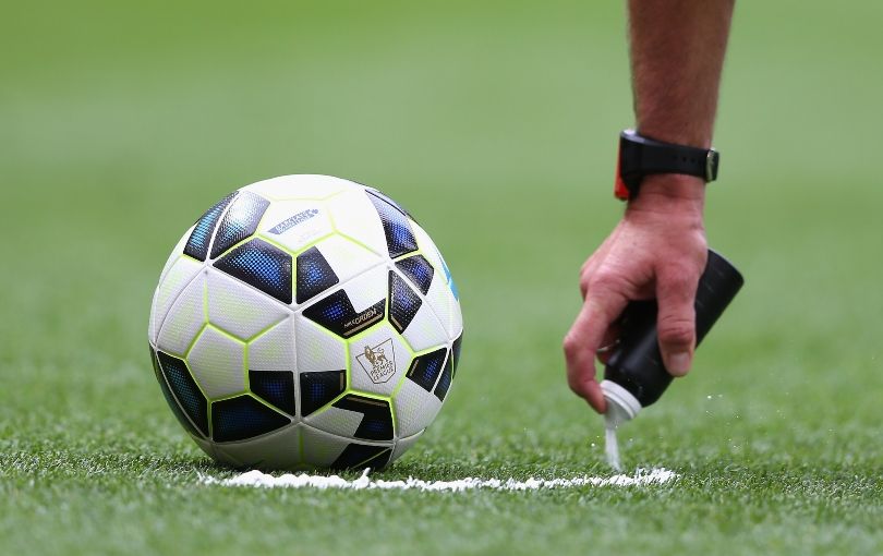 Referee using vanishing spray to mark out where a free kick is taken