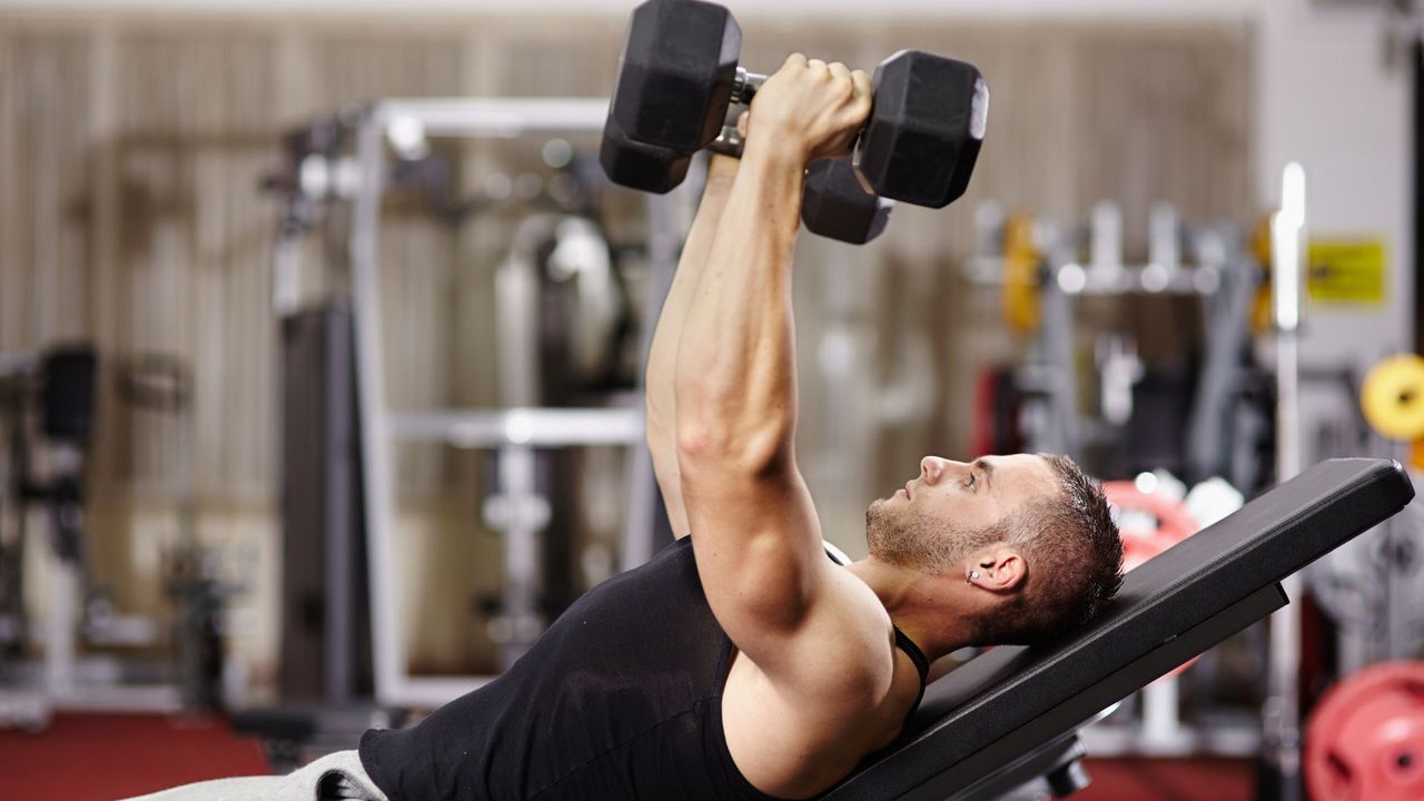 A man performing dumbbell flyes on weight bench