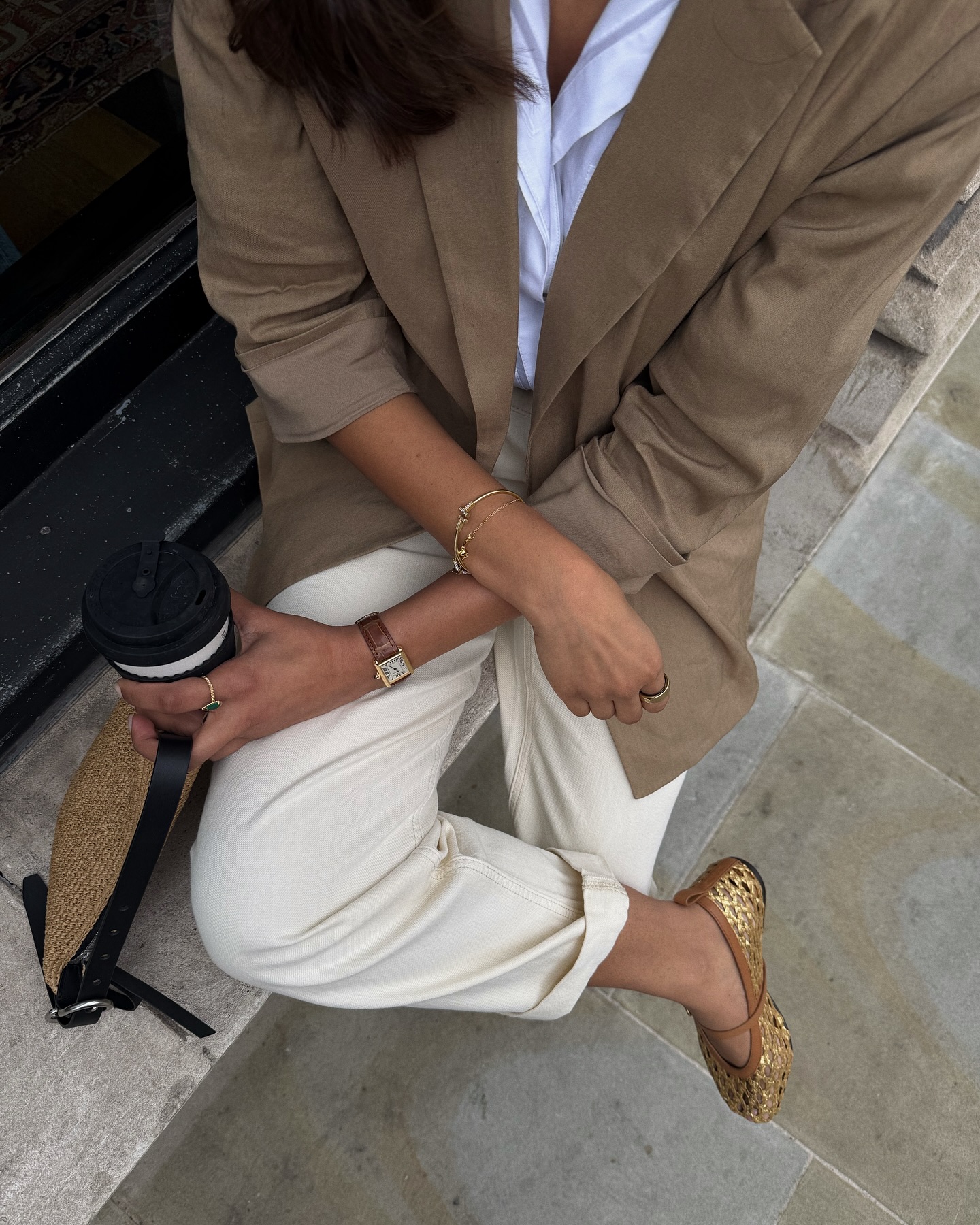 An image of @cocobeautea wearing a linen blazer with white jeans and gold woven ballet flats while in London.