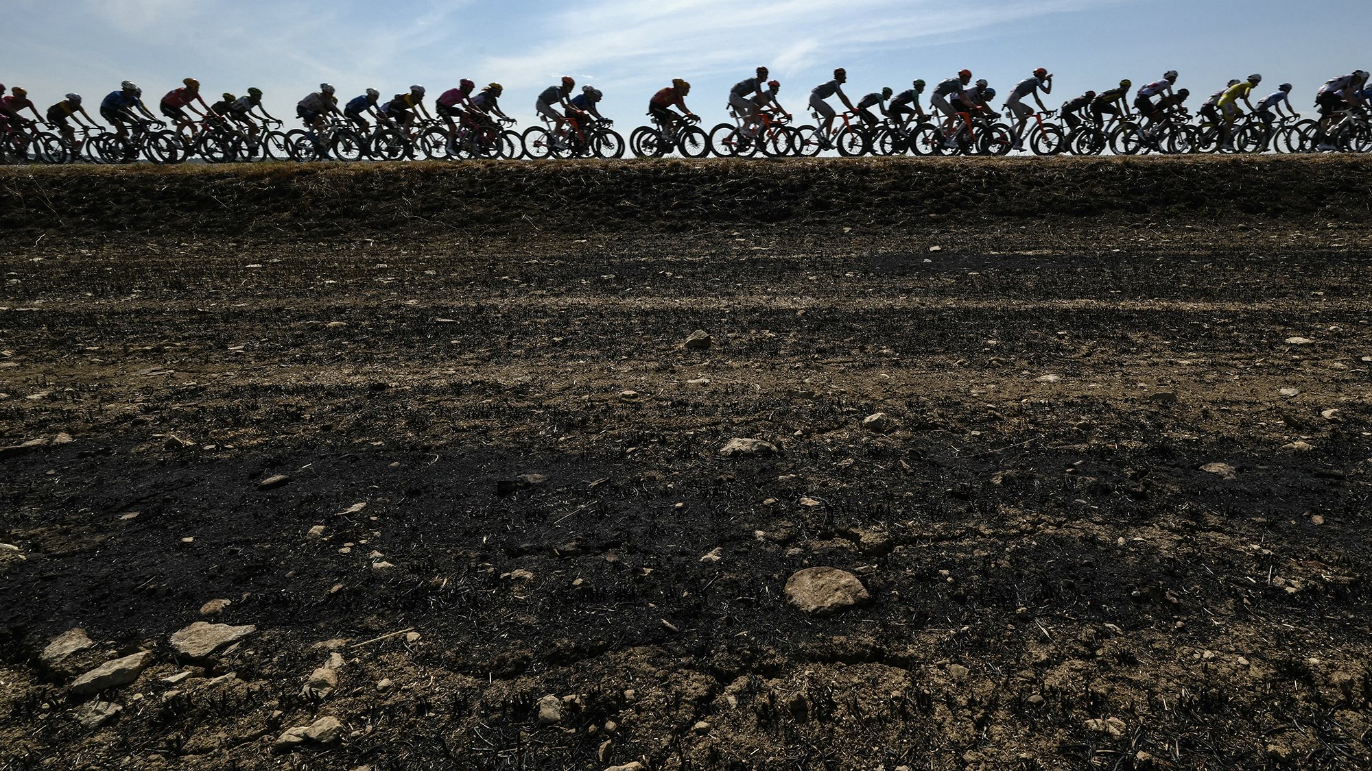 The peloton cycles past scorched fields during the 11th stage of the 113th edition of the Tour de France cycling race, somewhere between Vichy and Nevers in central France