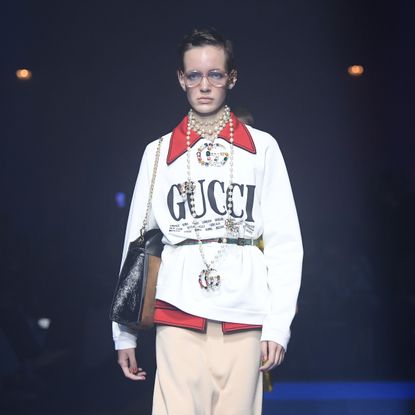 A model walks the runway in Gucci clothing.