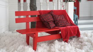 Two cushions and a blanket on a red bench