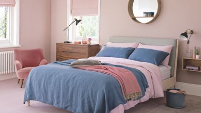 bedroom flooring ideas, grey upholstered bed with yellow throw, wooden stool at end, grey stripe carpet, charcoal black wall, white shutters, pops of pink pillows, wood side table, vases 