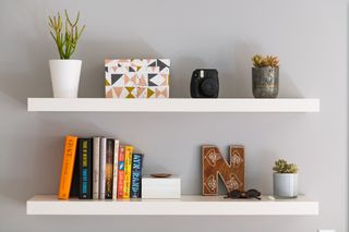 Two white shelves with little decorative pieces on.