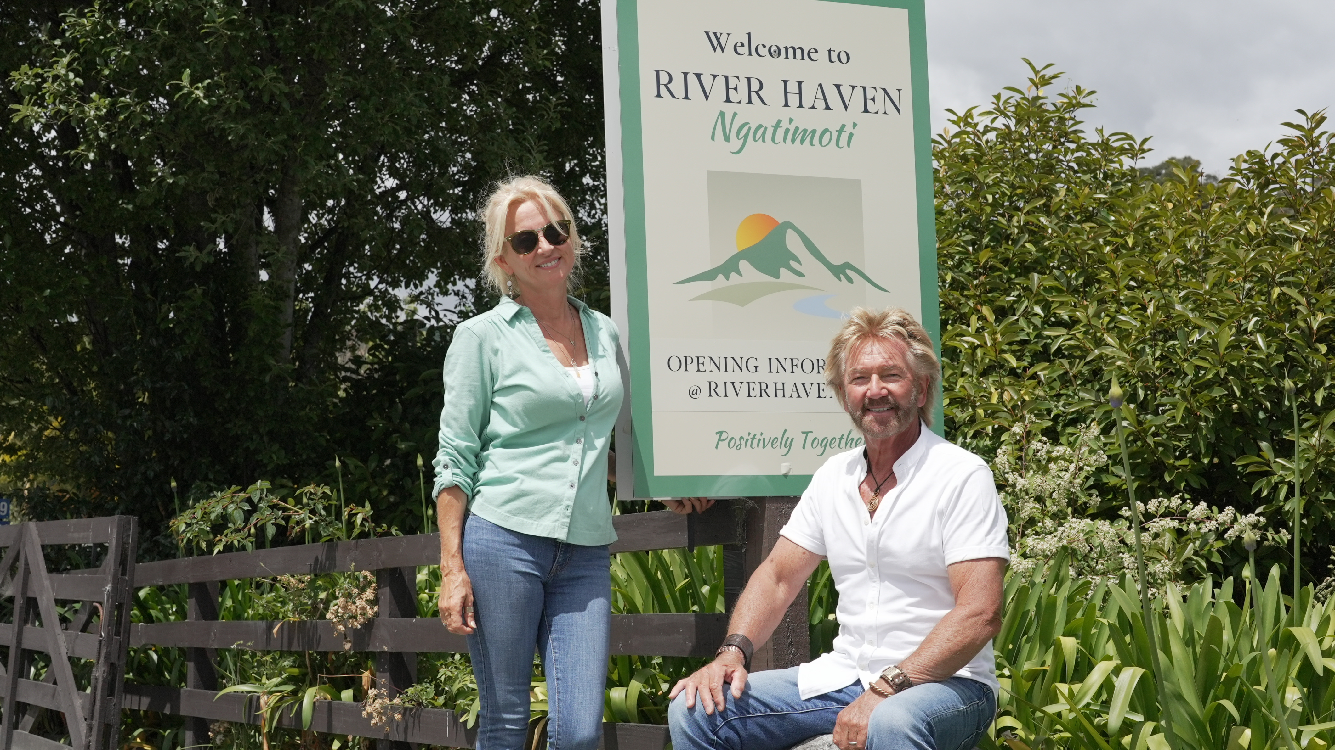Liz Davies with husband Noel Edmonds, both smiling and posing beside the sign for their business River Haven.
