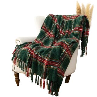 Green and red plaid blanket on a white armchair with pampas grass behind