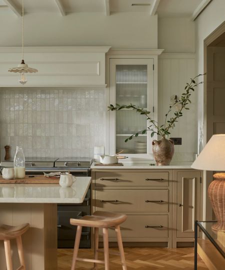 A kitchen with warm beige cabinets, white countertops, and a mix of tile and paneled backsplash