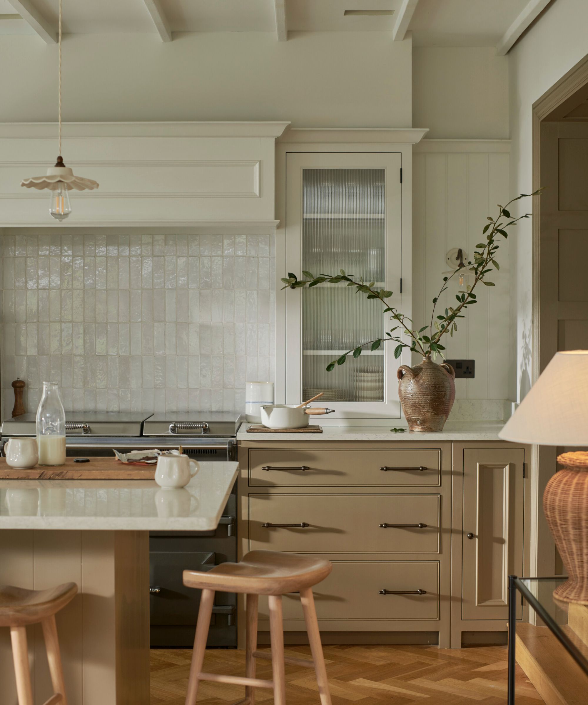 A kitchen with warm beige cabinets, white countertops, and a mix of tile and paneled backsplash