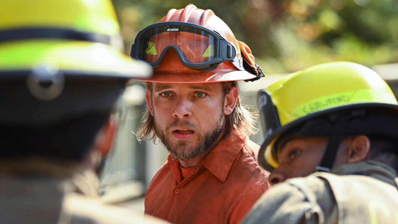 Max Thieriot blickt mit zwei anderen Feuerwehrleuten im Vordergrund auf Fire Country in die Ferne.