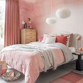 Bedroom with pink plaster walls and bed with feather light pendants