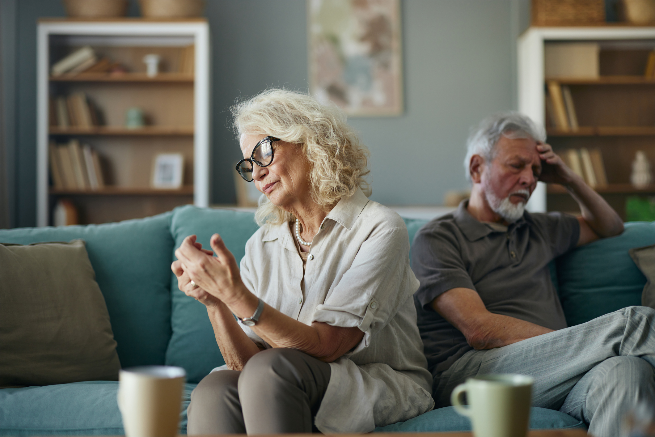 Careless mature woman ignoring her husband on sofa in the living room.