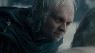 Tom Glynn-Carney as Aegon bending down and looking at Aemond (who is out of frame). 