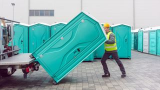 Man unloading Porta-potty from truck