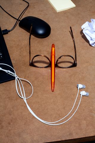Desk with eye glasses, pencil, ear phones, mouse and laptop.