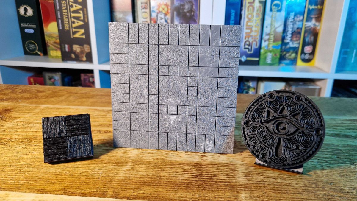 Items printed by the Elegoo Centauri Carbon on a wooden table, in front of board game shelves